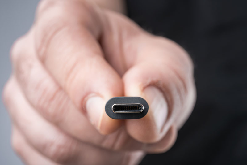USB Type C connector with a grey cable being held in hand. Shallow depth of field